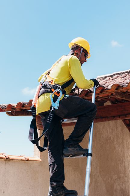 A person on a flat commercial roof clearing debris from around a rooftop drain before a storm.